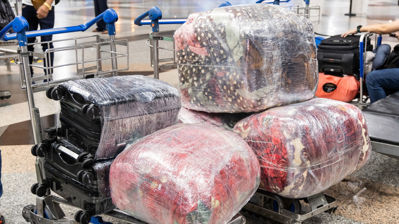 Airport carts carrying luggage wrapped in protective plastic