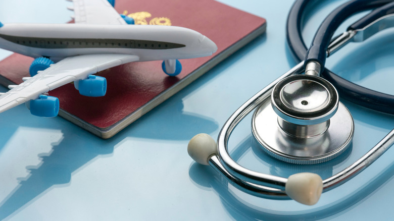 A passport and stethoscope next to a model airplane