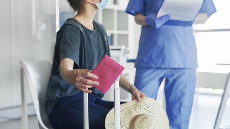 A traveler with her passport and luggage at a medical clinic