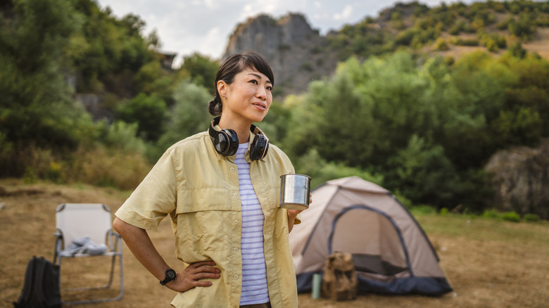 Person drinking from a cup at a campsite