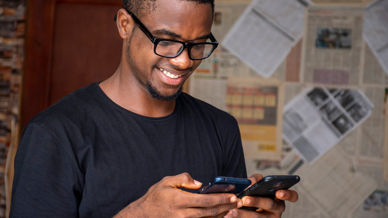 Smiling man holding two smartphones