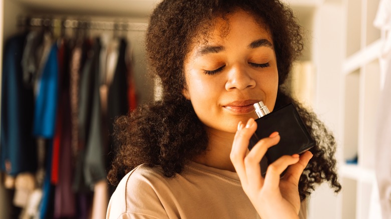 woman smelling perfume in bottle