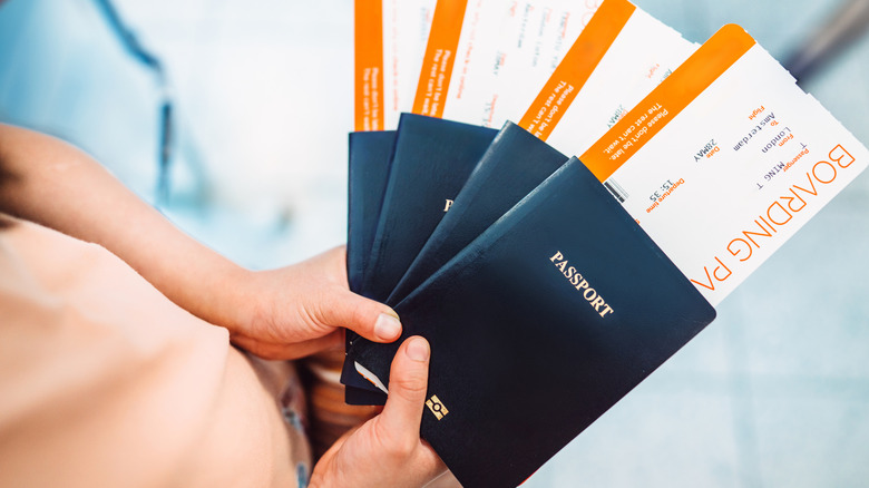 A traveler holding passports and boarding passes at an airport