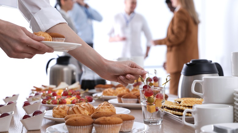 Person getting food from breakfast spread