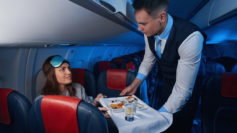 Flight attendant serving a passenger a meal