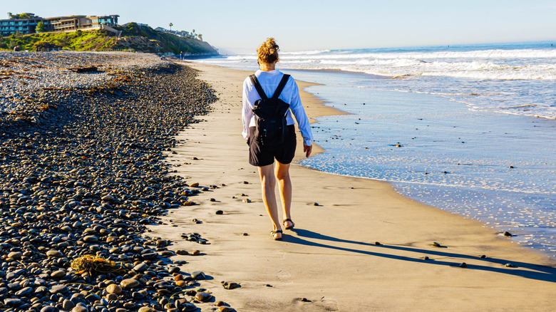 Female tourist walking the shoreline at South Ponto Beach