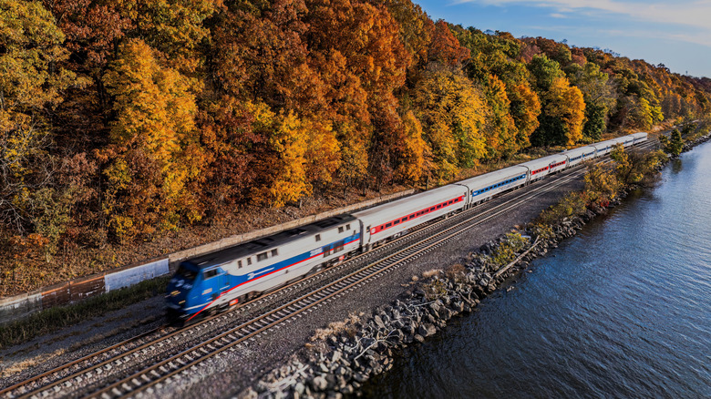 Amtrak train passing Hudson River with fall foliage