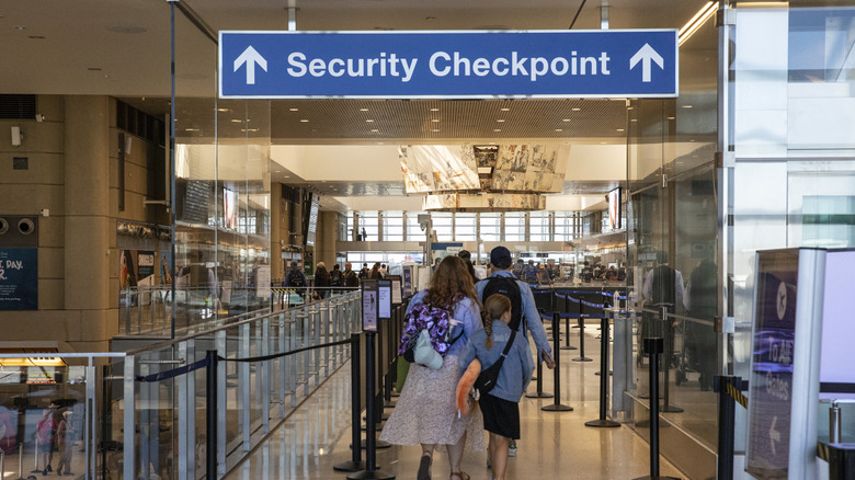 People walking to the security checkpoint at an airport