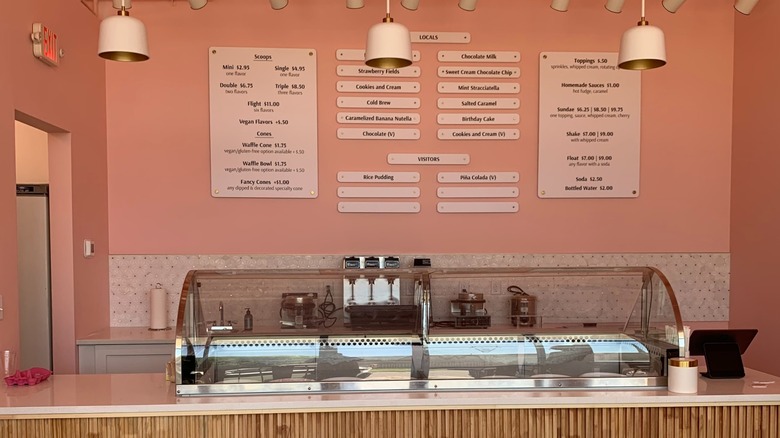 The counter inside Wandering Cone Creamery, surrounded by pink walls and a menu on the wall behind it