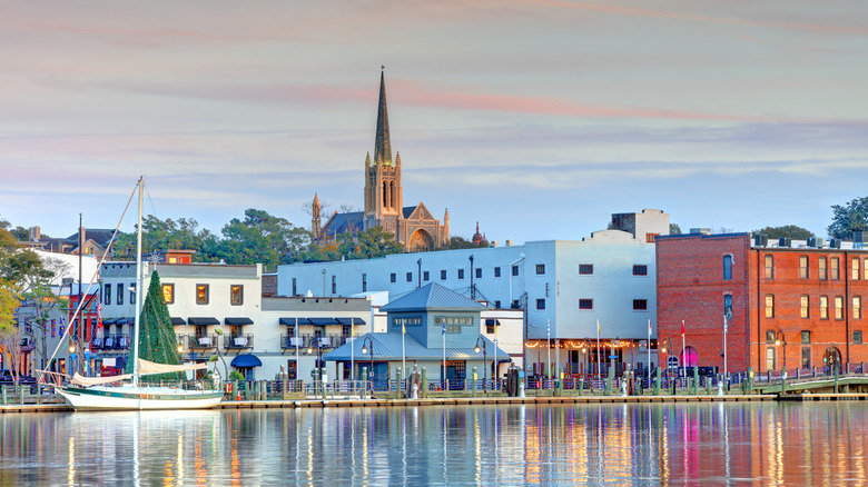 waterfront with sailboat, buildings, and church steeple in background