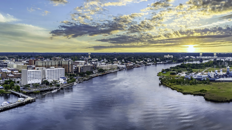 city buildings set along waterway with setting sun in background