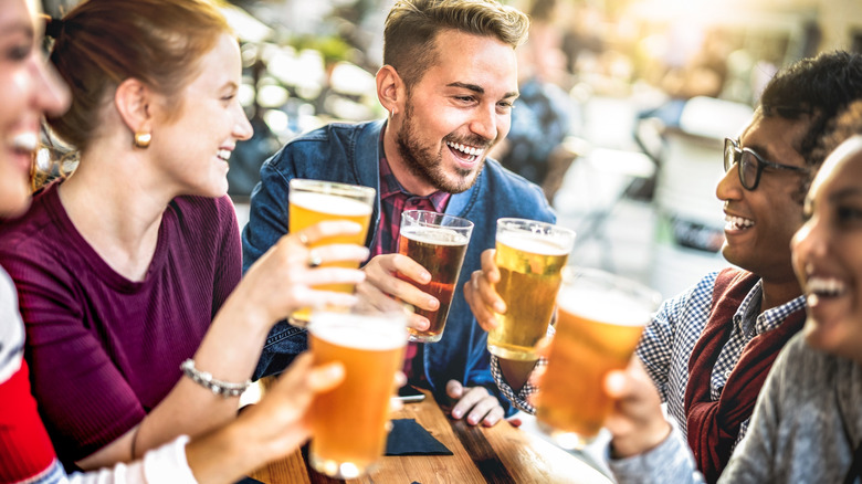 A group of people toast brewery beers in an outdoor space