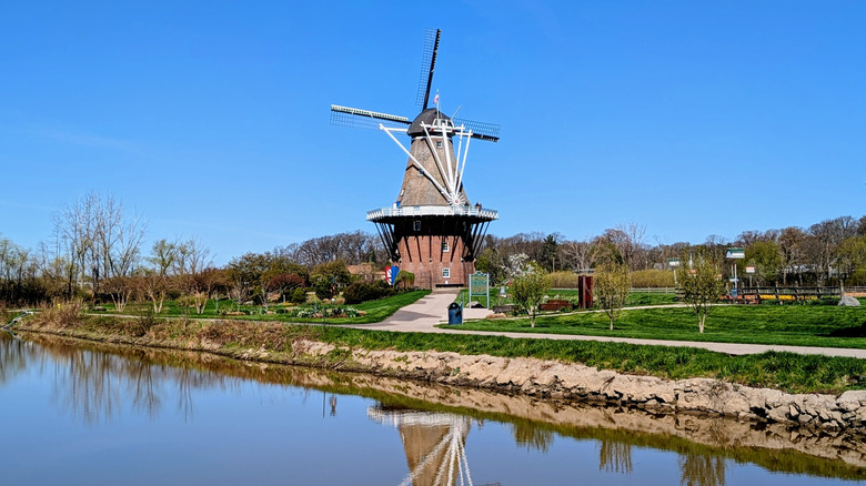 View of the De Zwaan windmill from the river on a sunny day at Windmill Island Gardens