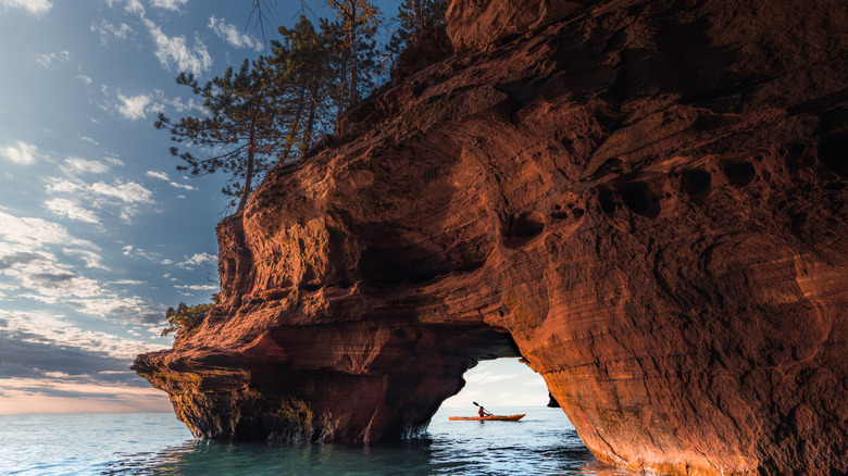 kayaker paddling near natural rock arch on large lake