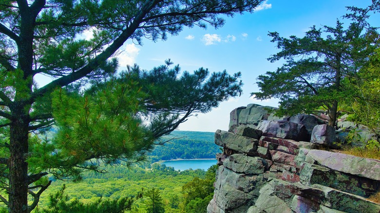 A summer's day view of a distant lake in a wooded valley from atop a rocky bluff at Devil's Lake State Park near Baraboo, Wisconsin