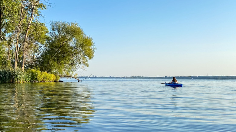 A woman sitting in a kayak on a sunny, peaceful Wisconsin lake