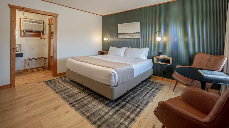 Single King Room with bed, leather chairs, wood floor, wool rug, and artwork