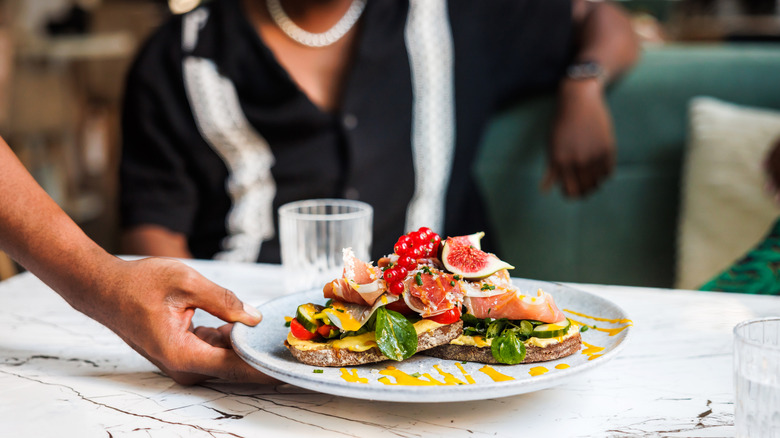A hand holding a fine dining plate, serving an elaborate toast