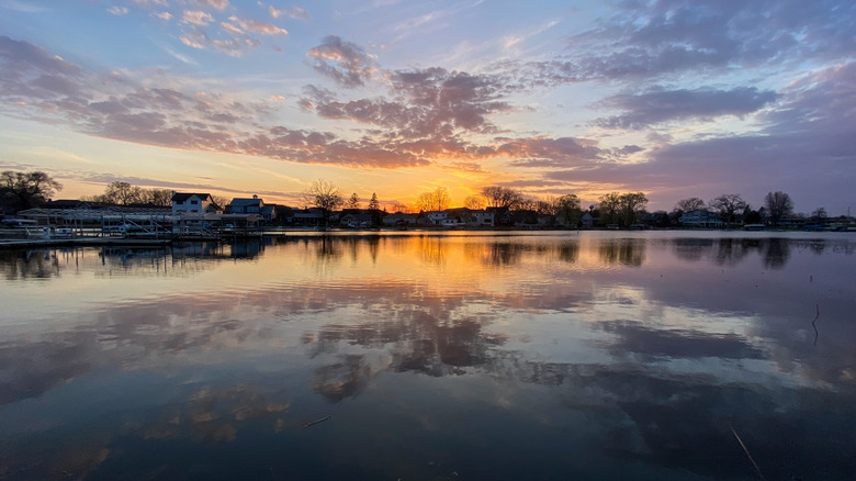Sunset colors reflected over a river, trimmed by houses and trees