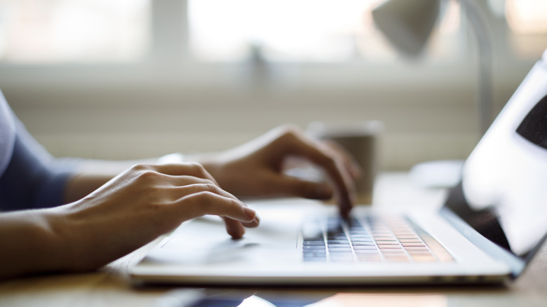 Close up of woman typing on a laptop