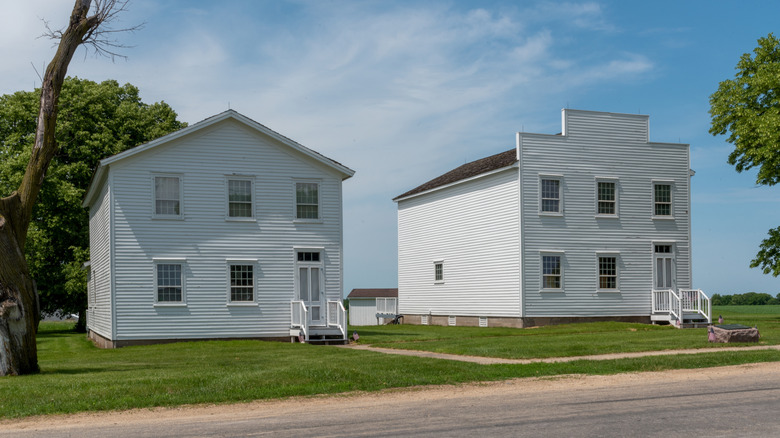 Two old time white buildings sit along the street beneath blue skies.