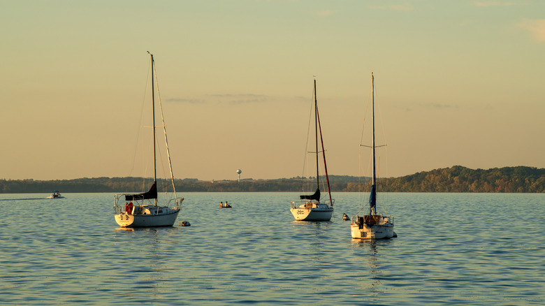 Three yachts on a lake at sunset, a range of hills in the background