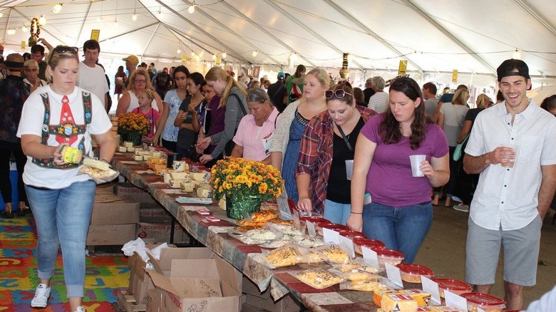 A line of attendees sample different cheeses with a smile at the Blair Cheese Festival