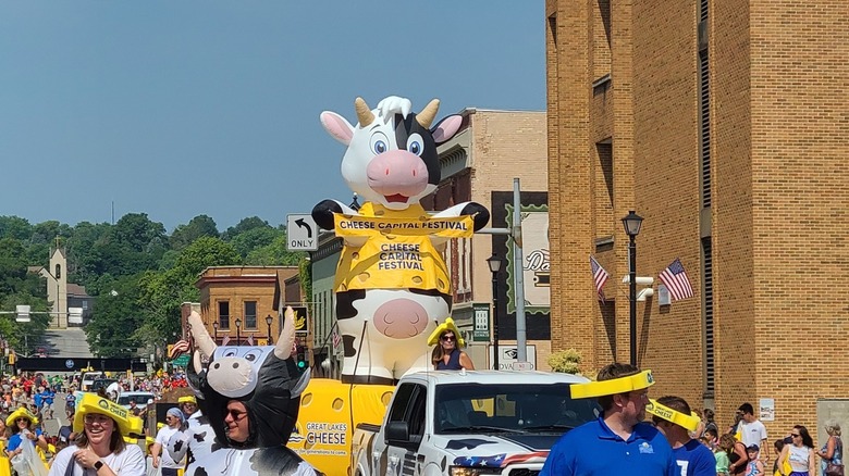 An inflatable cow heads down the street during a parade at the Cheese Capital Festival