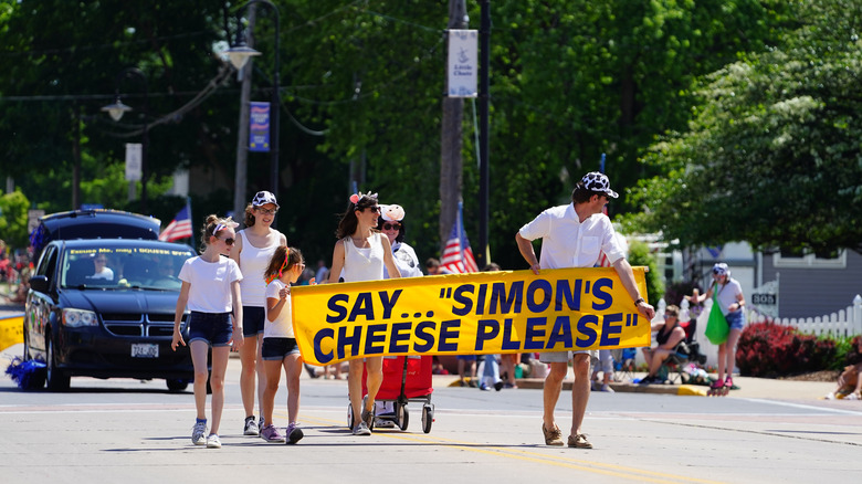 Parade-goers march down the street with a punny cheese-based sign at the Great Wisconsin Cheese Festival