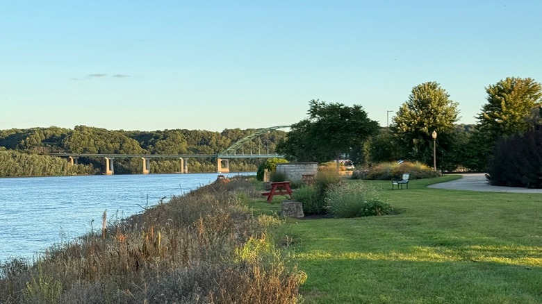 The quaint Riverside Park in Cassville, trimmed grass, a picnic table, a walk path on one side, and a bridge across the Mississippi in the distance