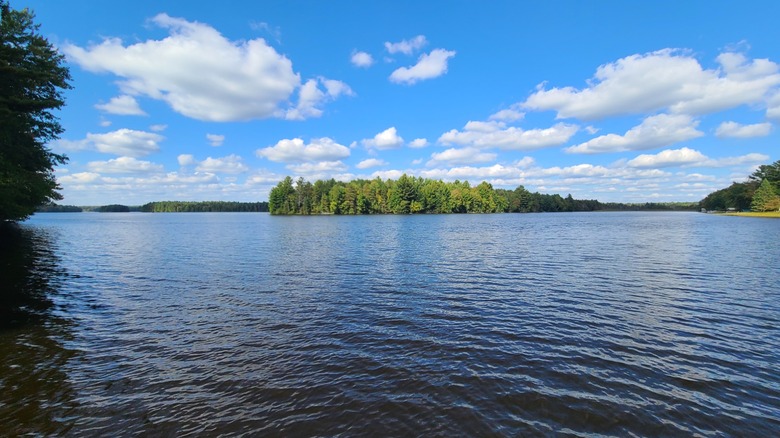A sunny summer day on the lake at Council Grounds State Park with a peninsula of trees across the water and the shoreline stretching off in the distance