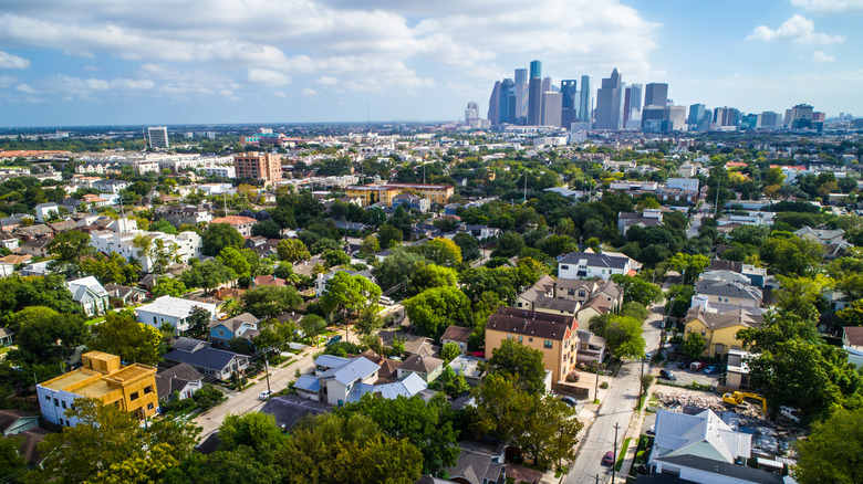 Aerial view of Montrose neighborhoods with Houston skyline behind.