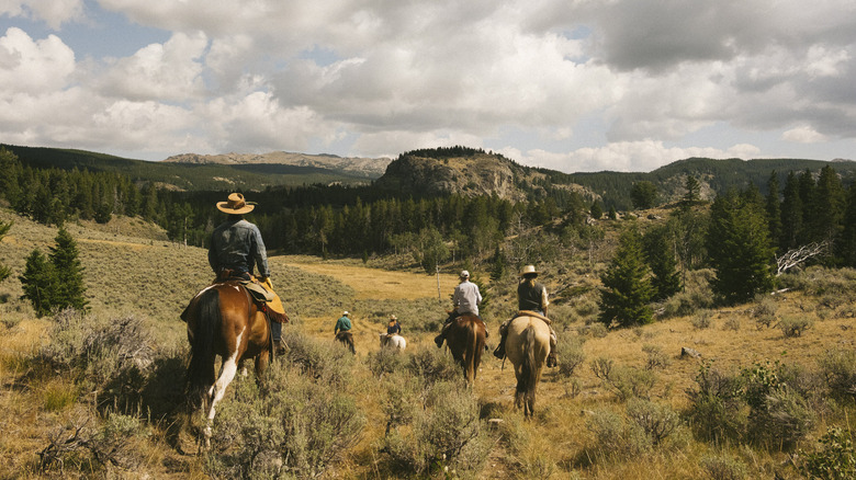 People on horses riding through Paintrock Canyon Ranch