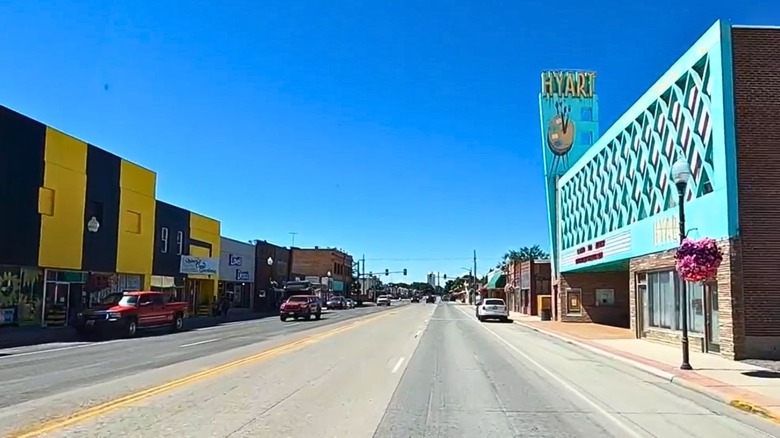 The main road through Lovell, Wyoming, with flowers hanging from lamposts, and businesses lining the way including the old time Hyart Theatre in a turquoise blue facade.