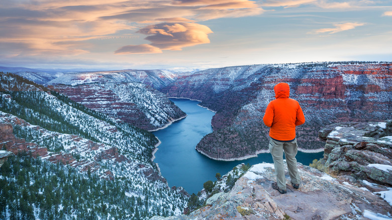 A man in an orange coat gazes into the snow-dusted canyon of Flaming Gorge, Wyoming