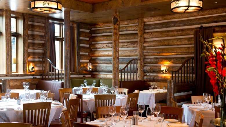 The dining room at Snake River Grill fashioned after a log cabin interior with wood log beams and elegant tables