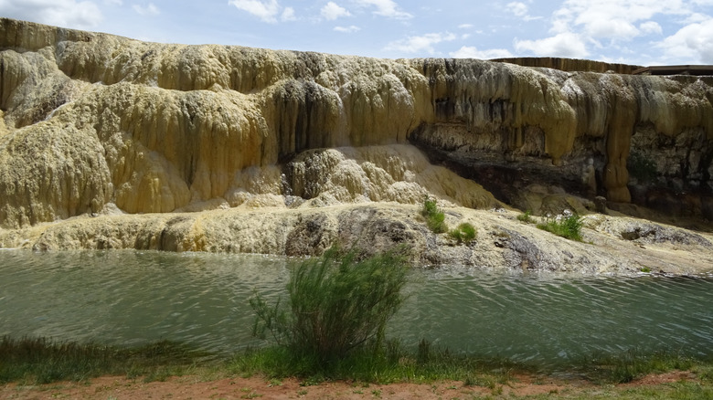 Cliff with mineral deposits creating cascading formations over turquoise pond, Thermopolis Hot Springs State Park, Central Wyoming