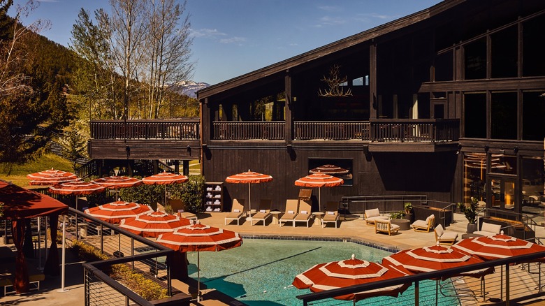 View of the outdoor pool, umbrellas, and lounge chairs at Trailborn Jackson Hole during the summer.