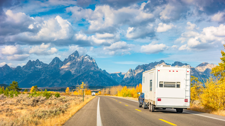 Camper traveling down the road in the foreground of the Grant Teton Mountains