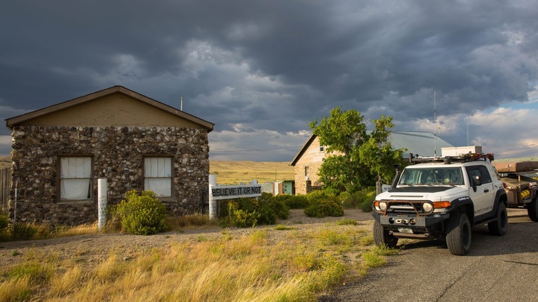 A car parked outside the Fossil Bone Cabin, a roadside attraction made with unusual material in Wyoming