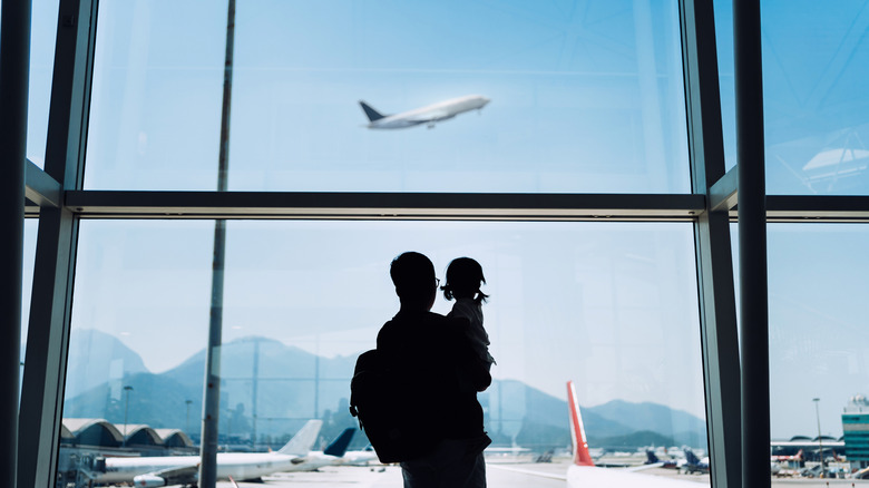 A parent and child watching an airplane