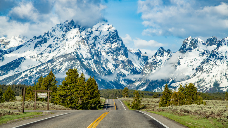 A road leading to snow covered mountains in Grand Teton National Park