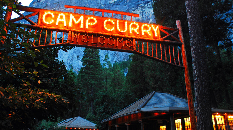 An illuminated sign reading "Camp Curry" hangs in front of the main lodge at Camp Curry in Yosemite.