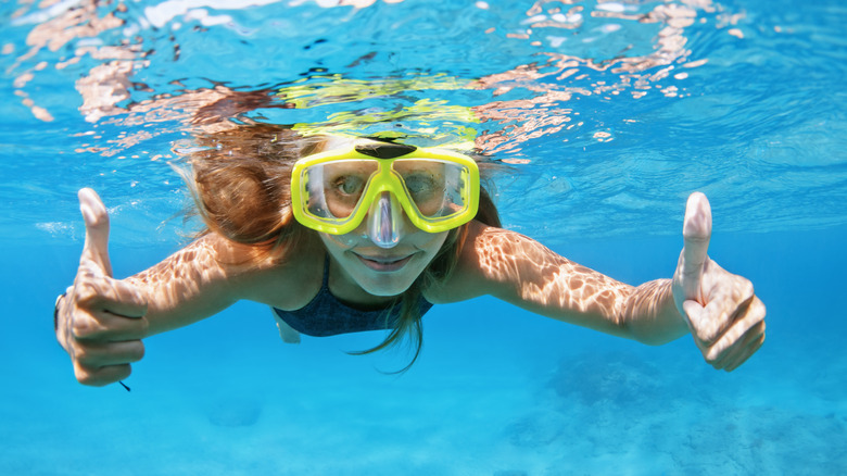 woman in snorkel mask gives thumbs up