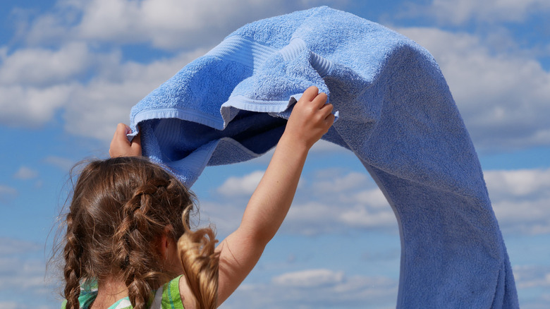 Little girl shaking out beach towel