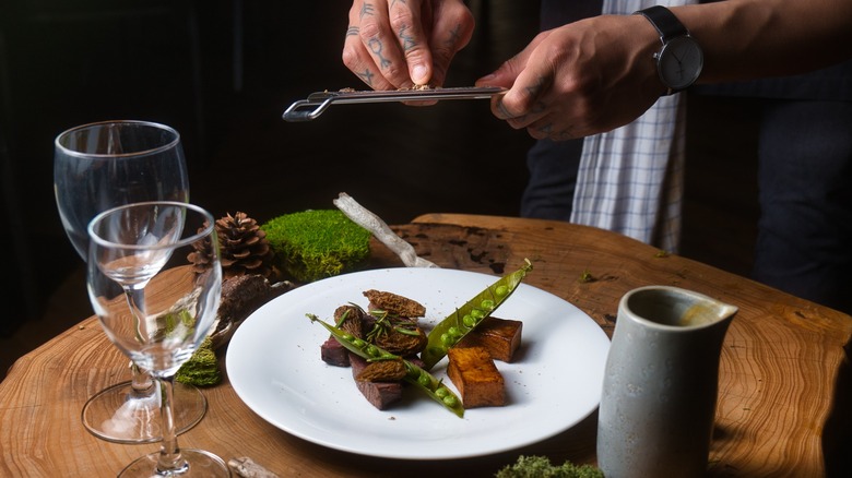 A chef puts finishing touches to a caribou dish served with Labrador tea
