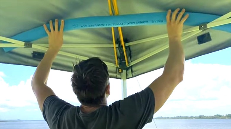 Person holding up pool noodle on tent