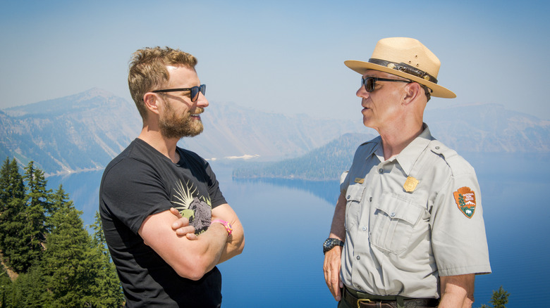 An Oregon state park ranger talking to a visitor with a beautiful lake backdrop