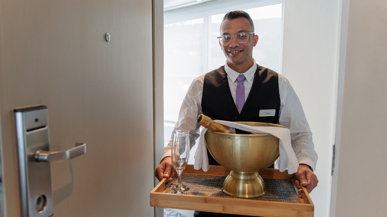 A butler at a hotel holding a tray with champagne and champagne flutes