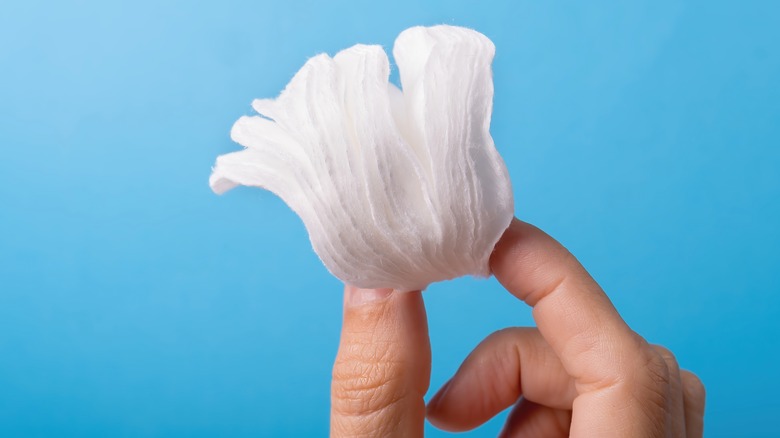 A person holding cotton pads